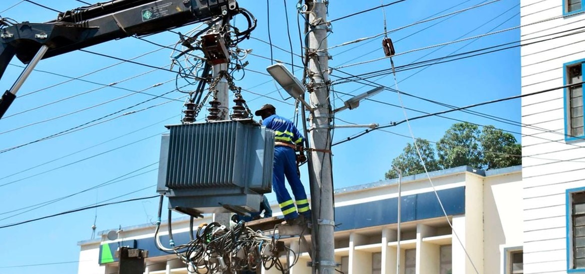 electrician standing on a electical concrete pilar, repairing transformer