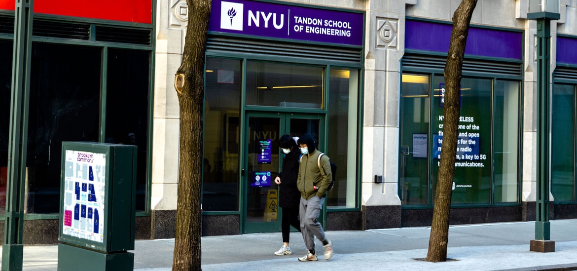 Two people walk past an entrance of a building with N.Y.U. Tandon School of Engineering sign above the enterance